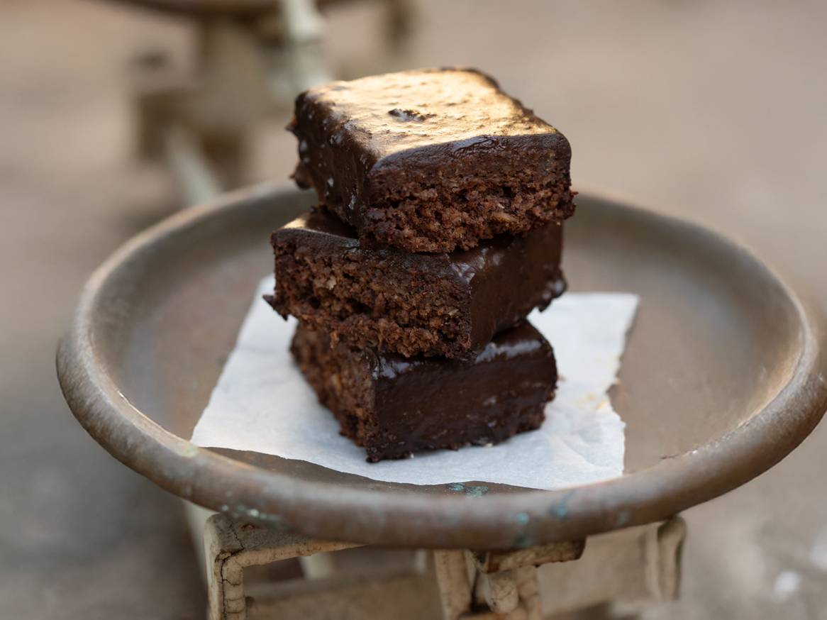 Tri čokoladna kolača s glazurom složena na starinskoj vagi.