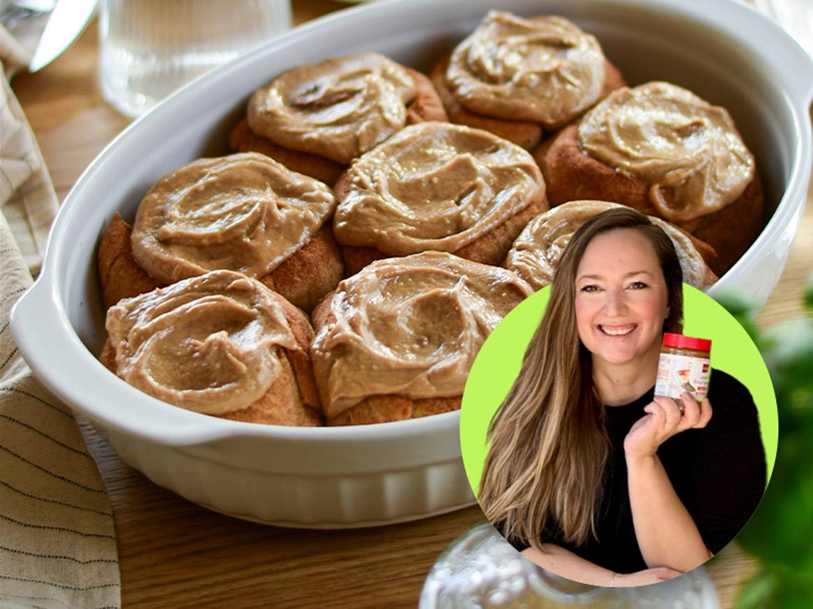 Žena drži staklenku maslaca od kikirikija pored posude s pecivima s glazurom.