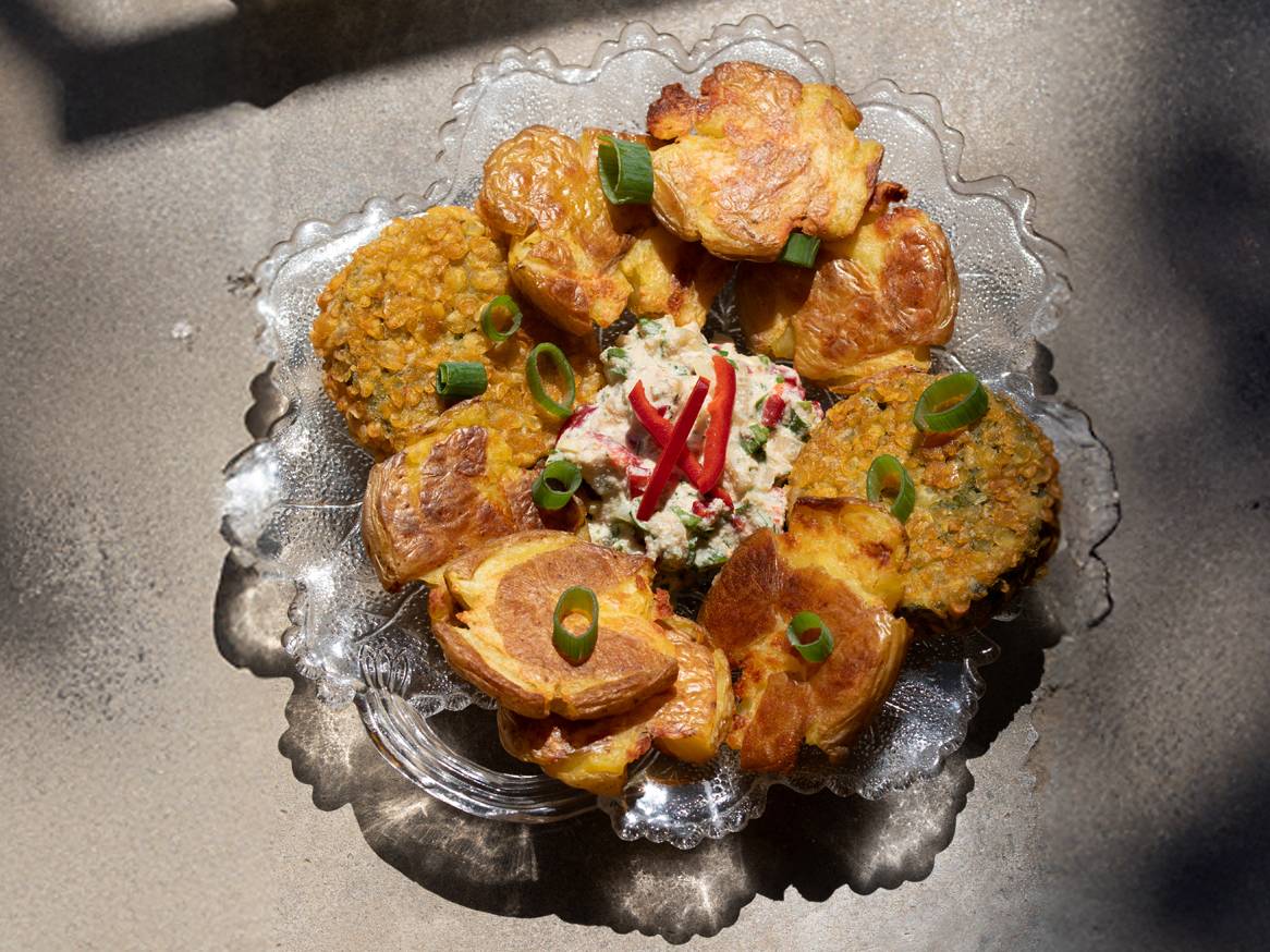 Hrskavi pečeni krumpir, popečci od leće i kremasti umak s paprikom na staklenom pladnju.