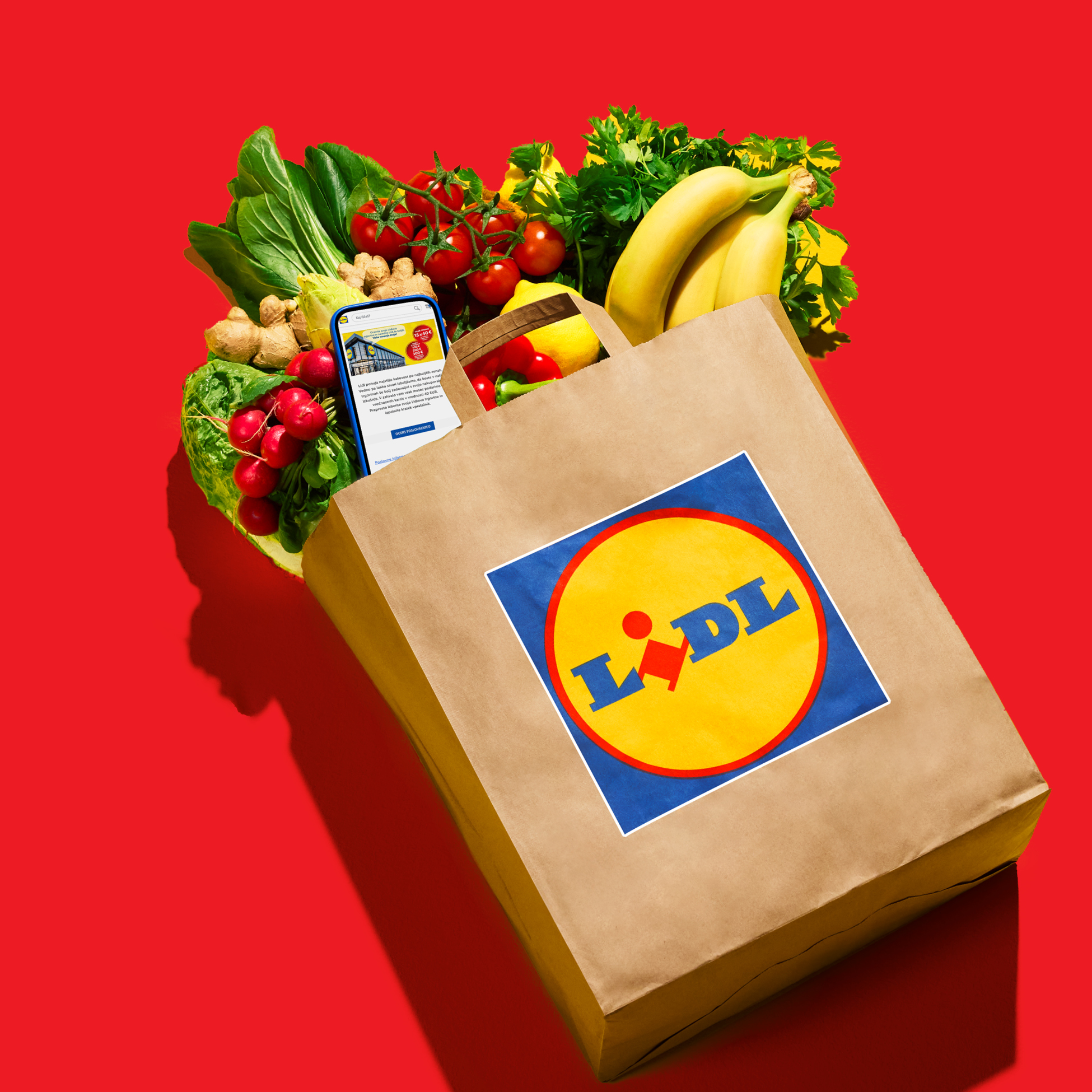 Papirnata vrećica puna svježeg voća i povrća, s mobilnom aplikacijom za kupovinu.