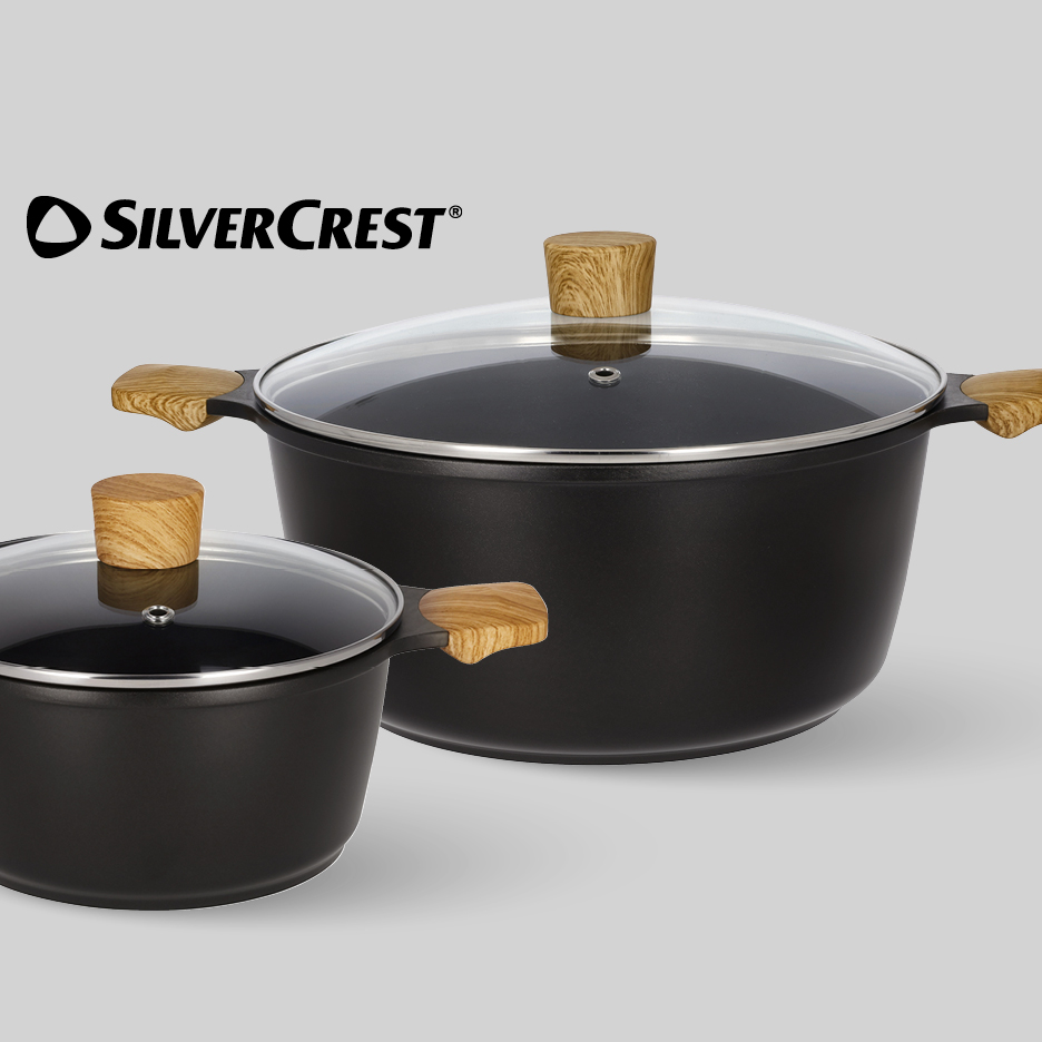 Set crnih lonaca s drvenim ručkama i staklenim poklopcima.