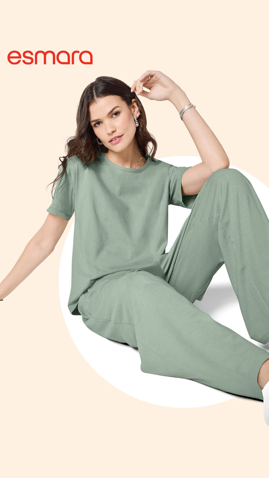 Žena u opuštenoj, svijetlozelenoj majici kratkih rukava i širokim hlačama, sjedi na podu.