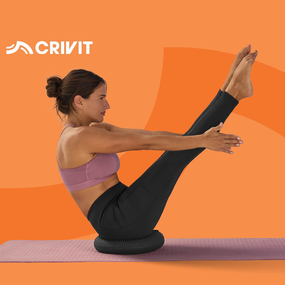 Žena radi vježbe za trbušnjake na balansu jastuku na prostirci za jogu.