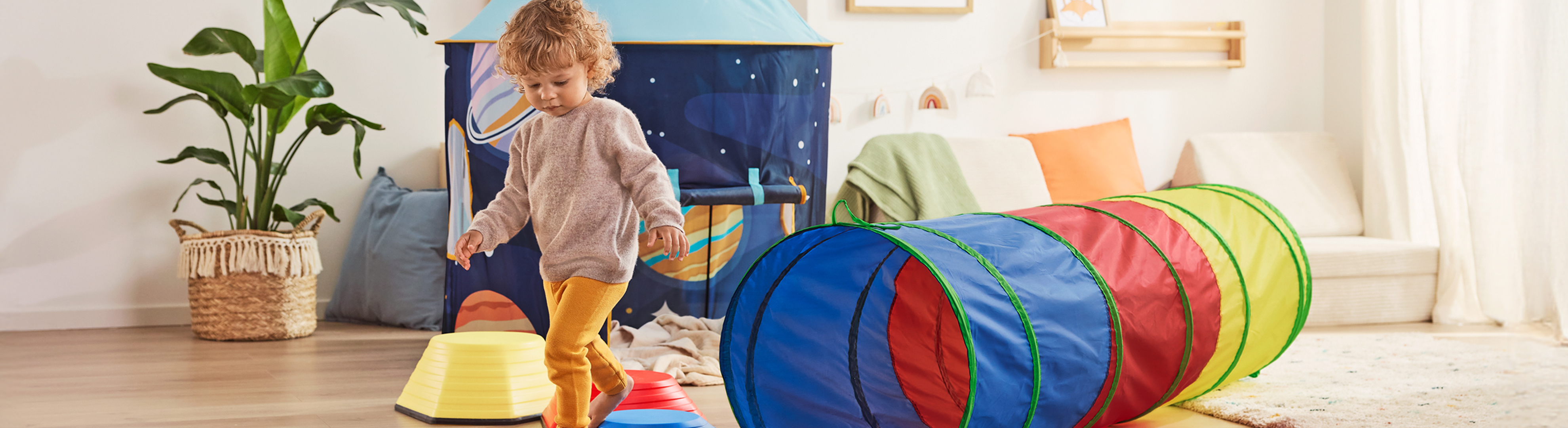 Dijete se igra s tunelom za igru i podnim stepenicama u dnevnoj sobi.
