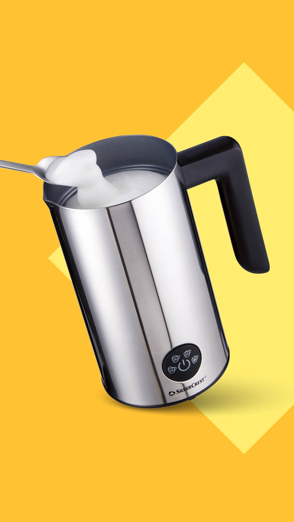 Srebrni pjenilac mlijeka s pjenom na žlici na žutoj pozadini.