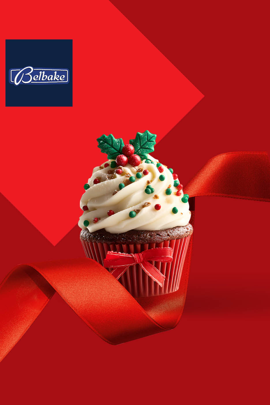 Belbake božićni cupcake s bijelom glazurom, zelenim listićima i crvenim bobicama, omotan crvenom vrpcom.